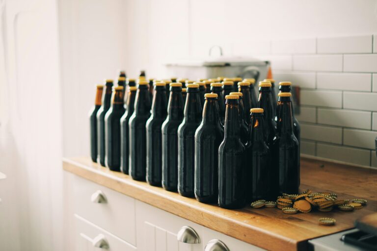Bottles of home brewed beer lined up on a shelf.